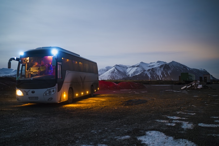 white and black bus running near the mountain