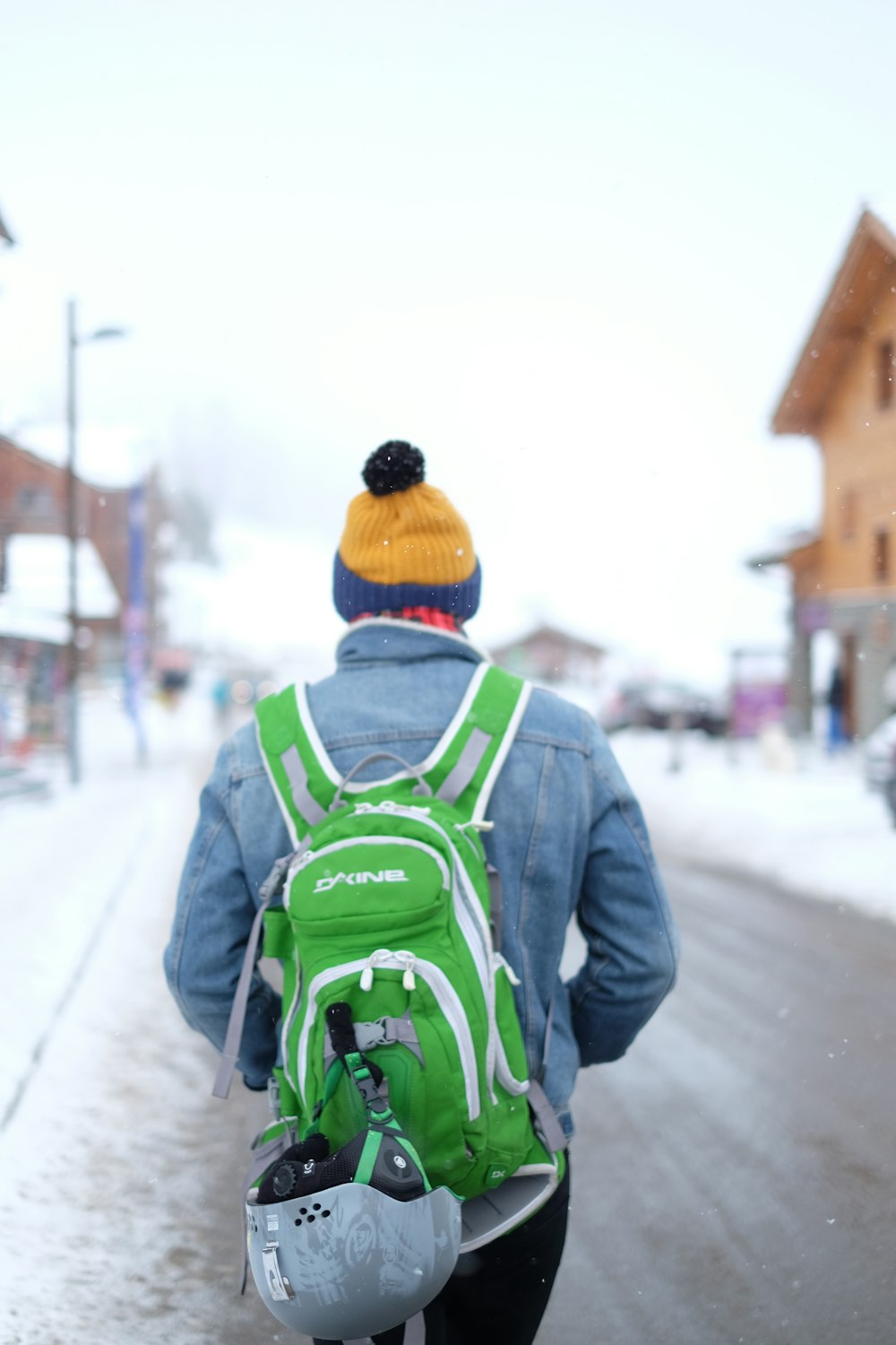 man walking on road with green and white backpack