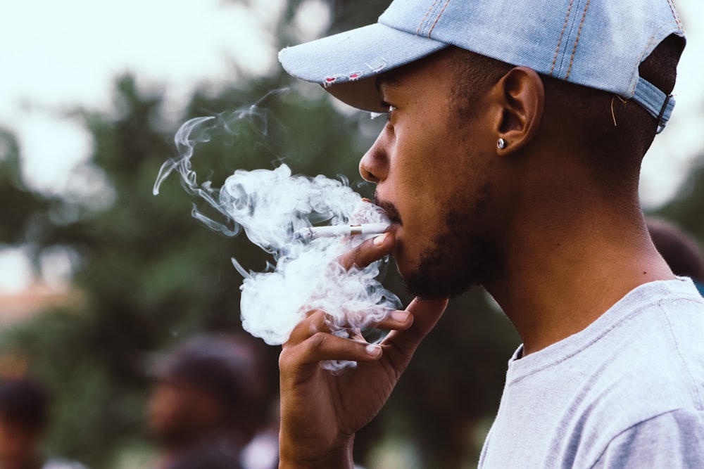 man smoking with blue denim cap