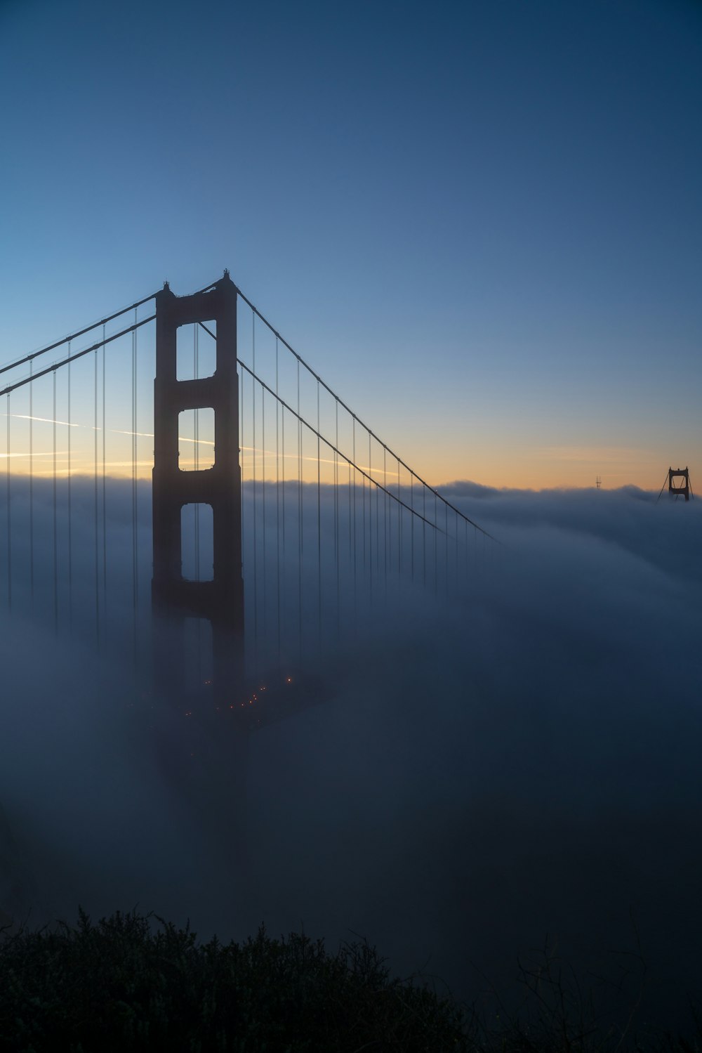 silhouette of full-suspension bridge covered with fog at daytime