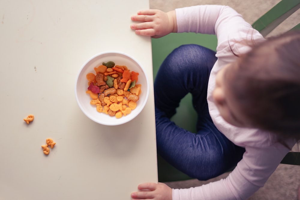 toddler sitting in front of bowl on top of table