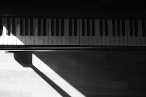 A minimalist black and white photo of a piano keyboard with soft shadows.