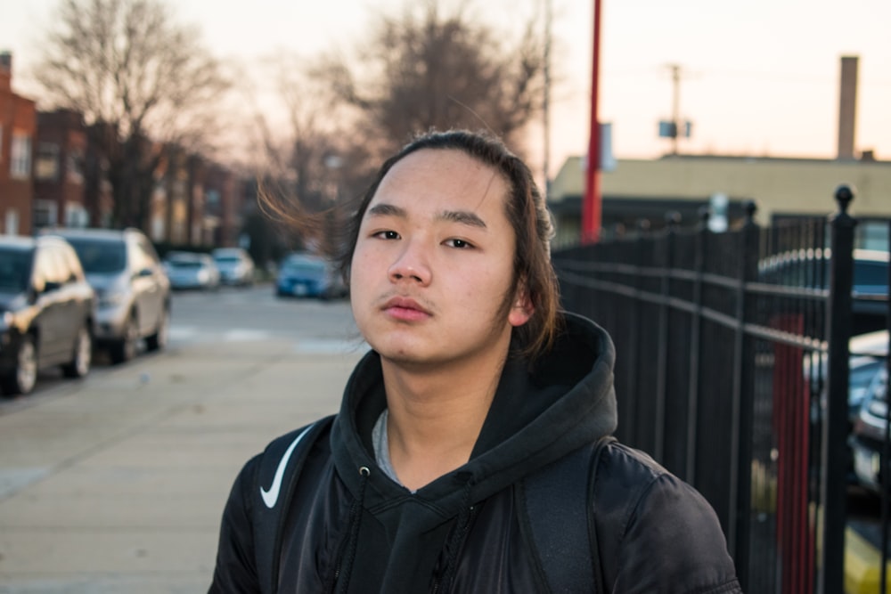 man standing outside near metal fence during daytime