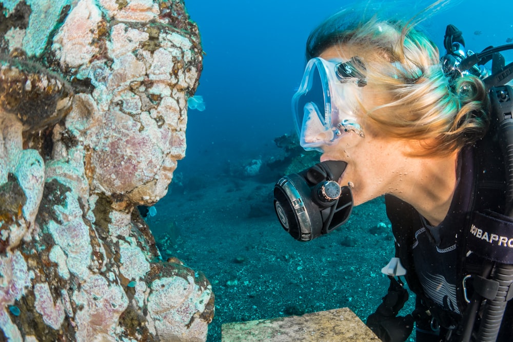 man underwater looking at religious statue