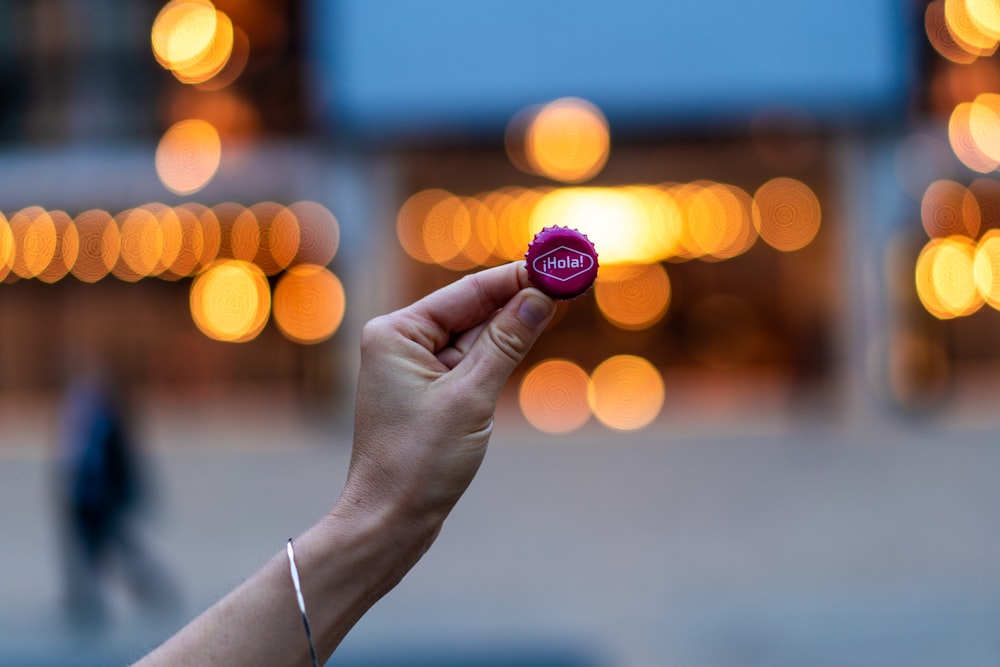 person holding purple bottle lid with bokeh background