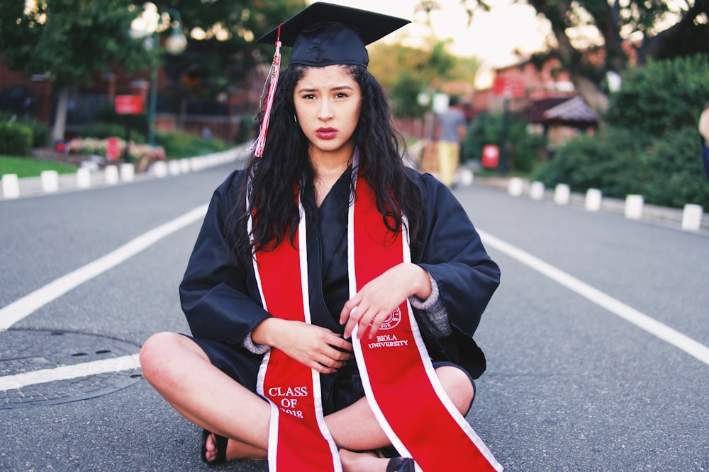 woman sitting on gray asphalt road