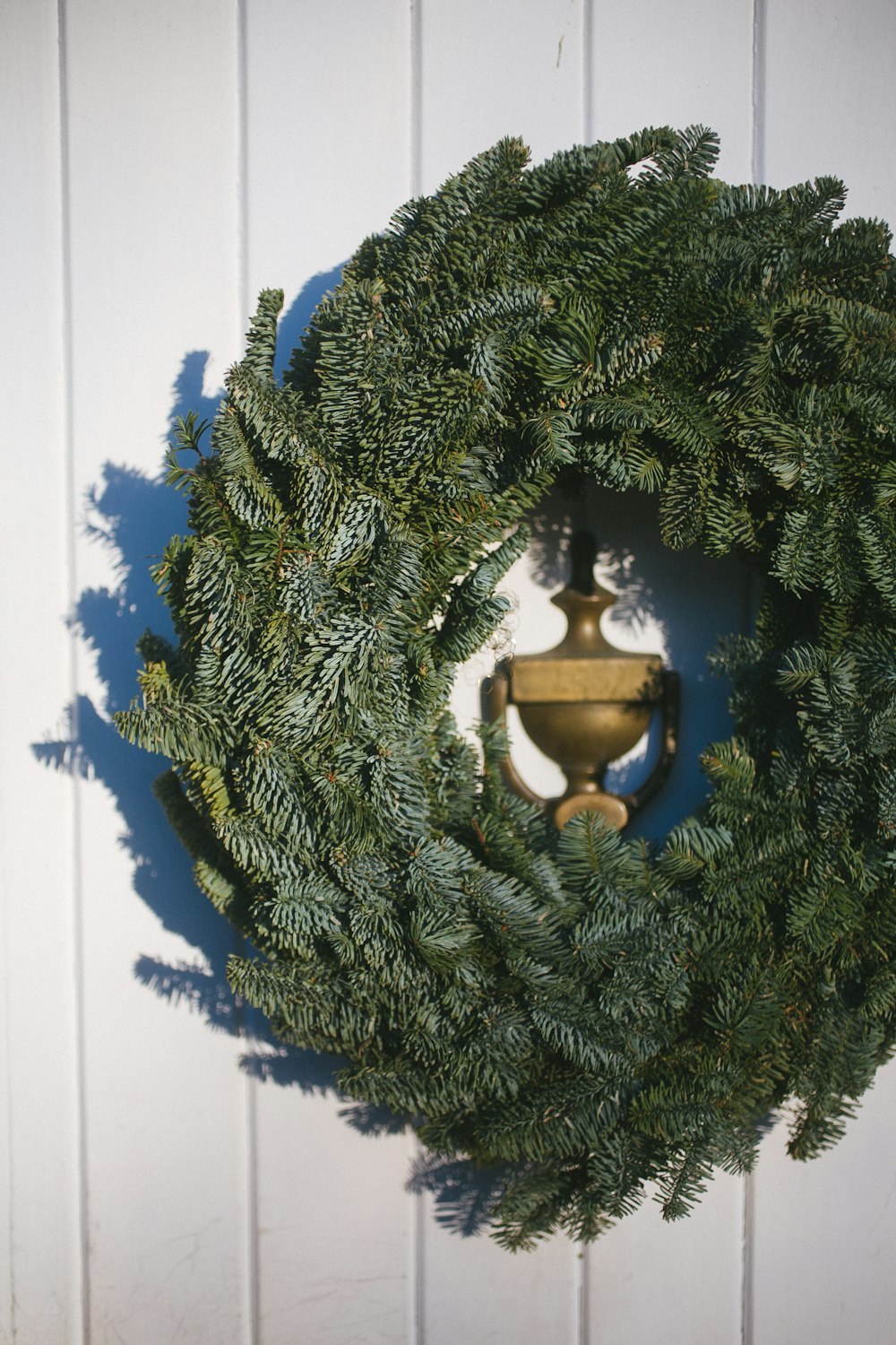 green wreath around brass door knocker