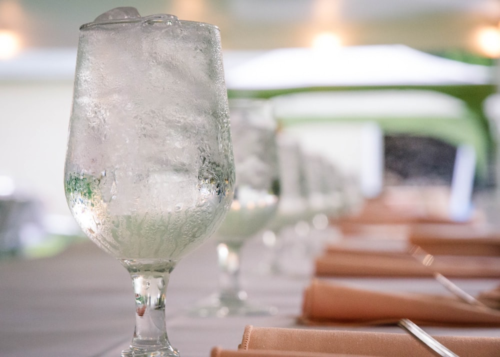 clear glass water filled goblet on top of table