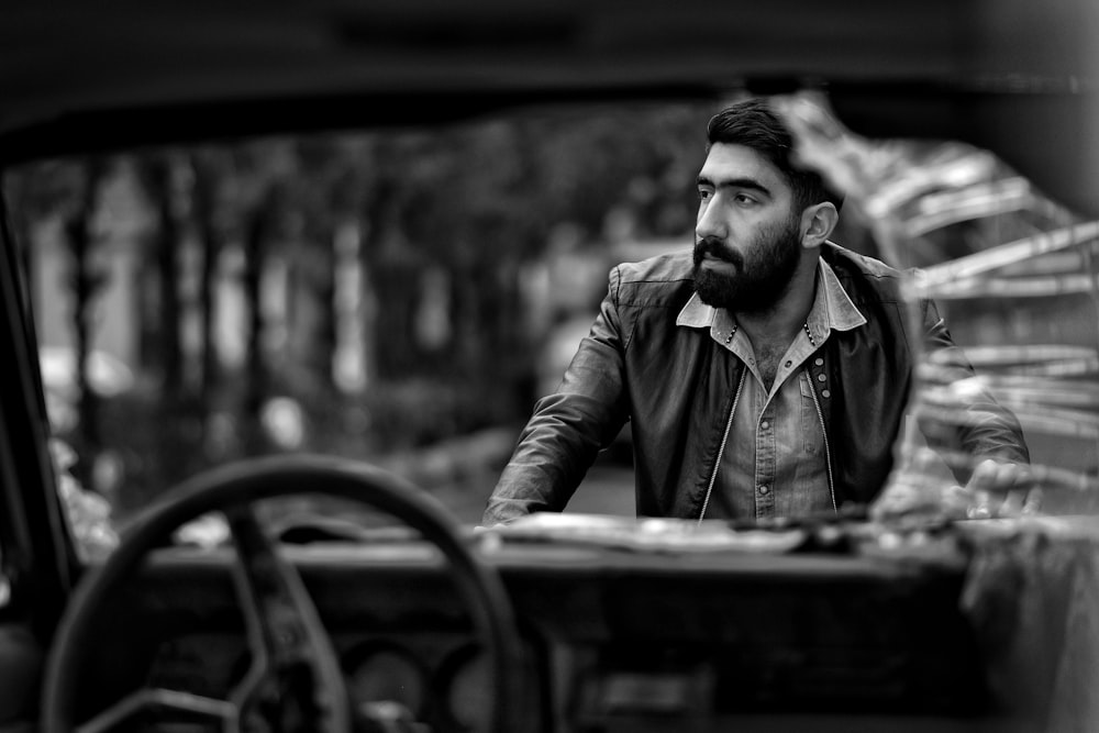 man wearing jacket standing beside vehicle