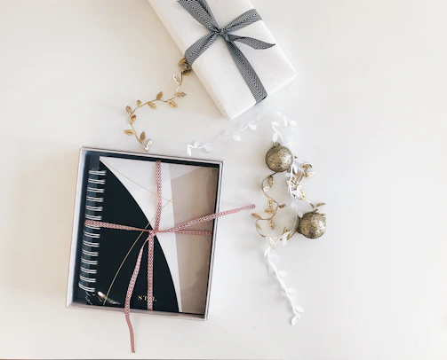 A beautifully arranged notebook gift box featuring elegant ribbons and rustic paper textures.