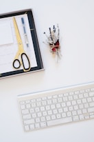 silver Apple Keyboard near black board and gray scissors