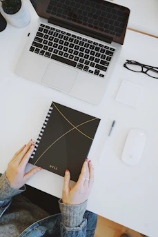 A person organizing a workspace with a laptop and notebook.