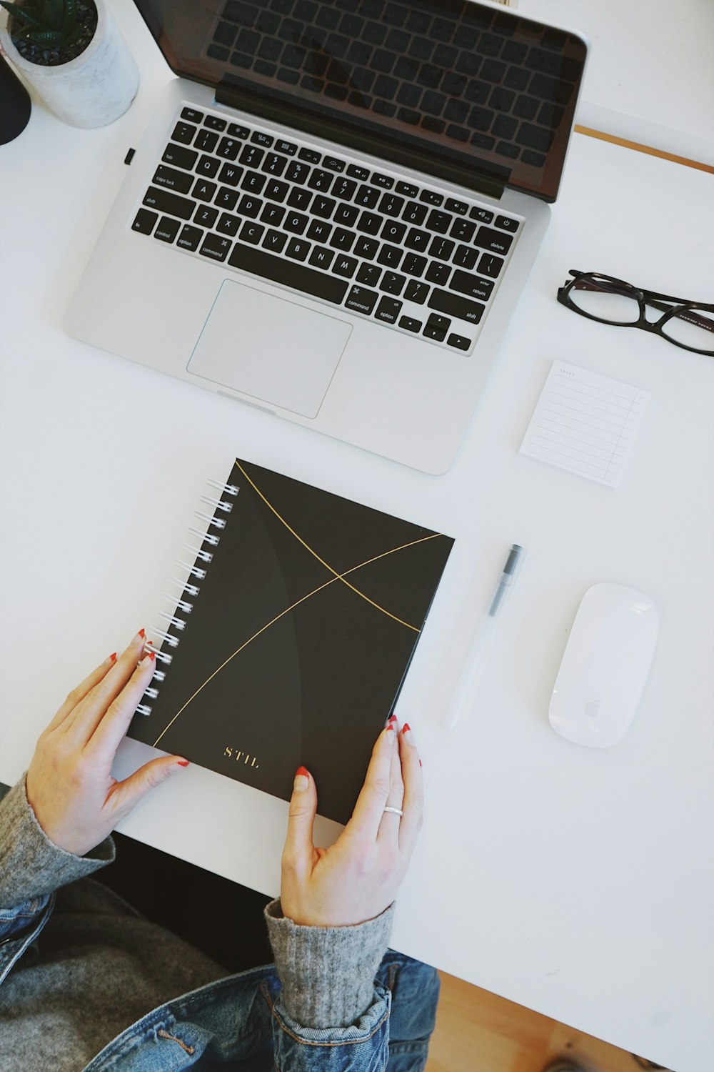 Persona sosteniendo el cuaderno cerca de la computadora portátil