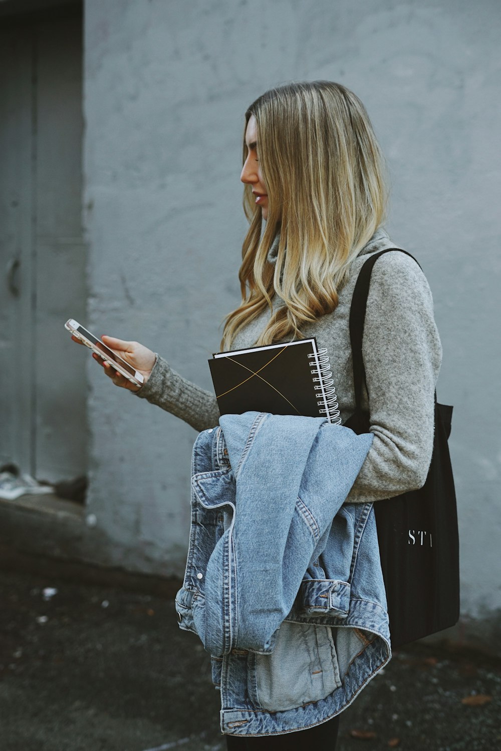 mulher segurando jaqueta jeans e telefone