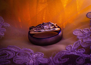A couple's ring set displayed on a delicate lace cloth with soft lighting.