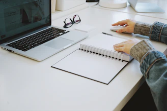 person touching white spiral notebook