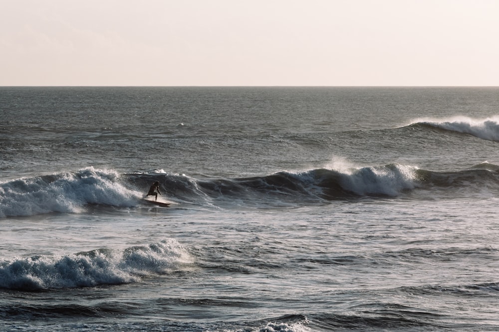 persona che fa surf nelle onde dell'oceano durante il giorno