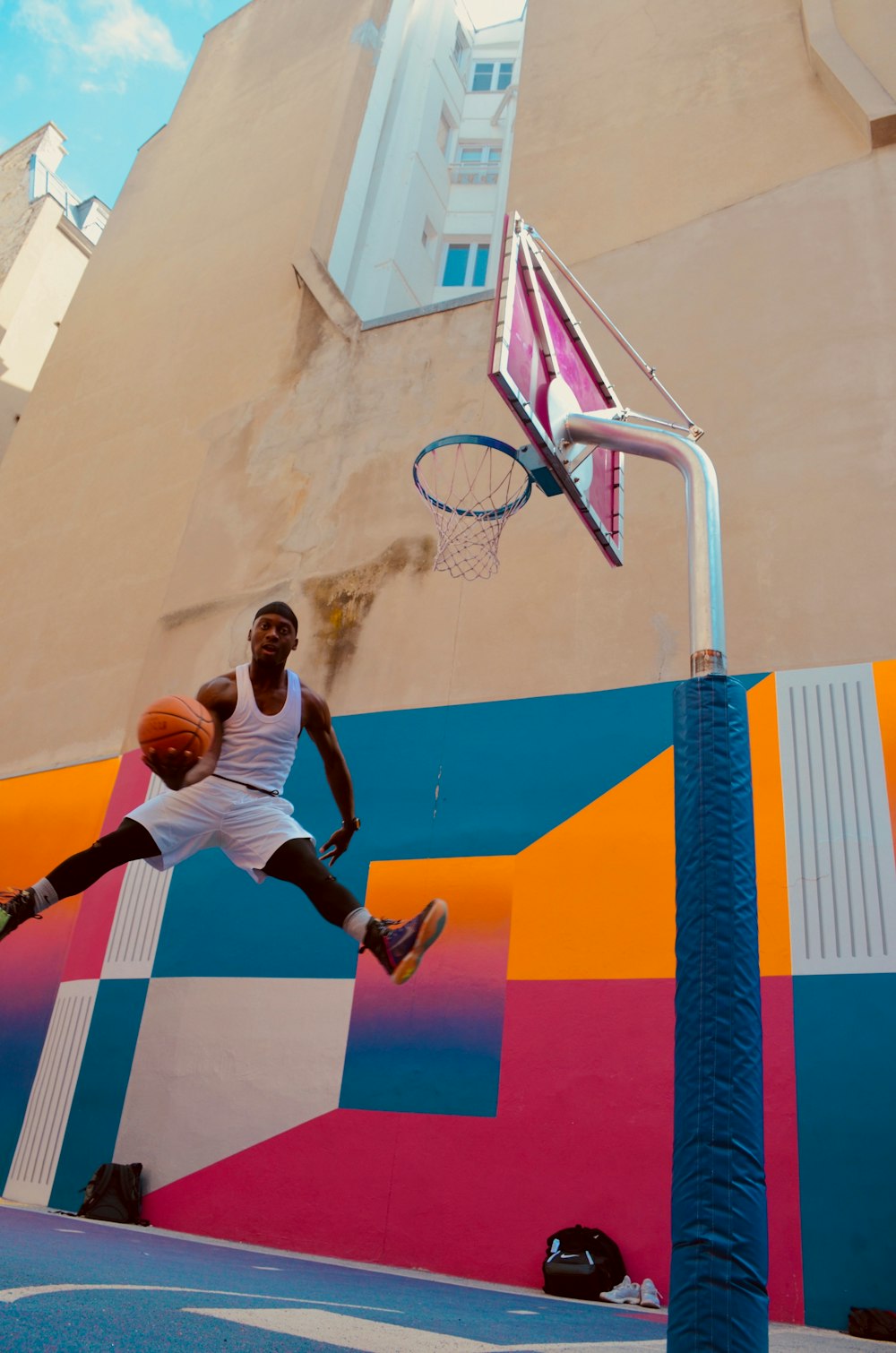 man holding basket ball near concrete building