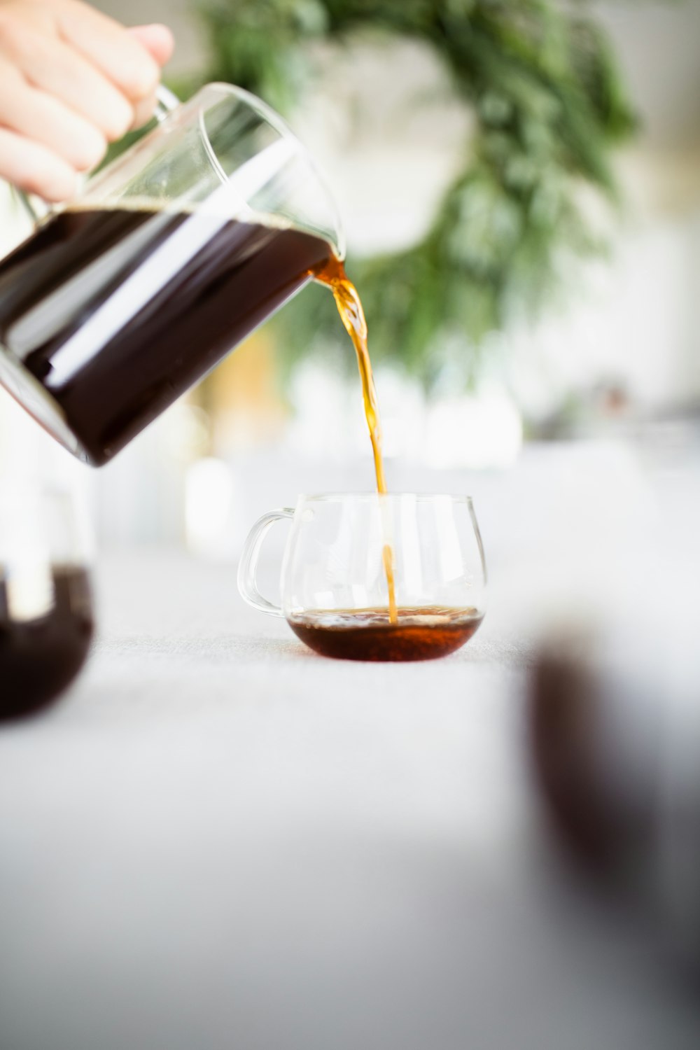 coffee from clear glass pot being poured into clear glass cup