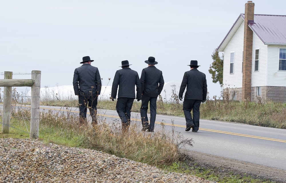 Quatro homens caminhando em estrada de asfalto