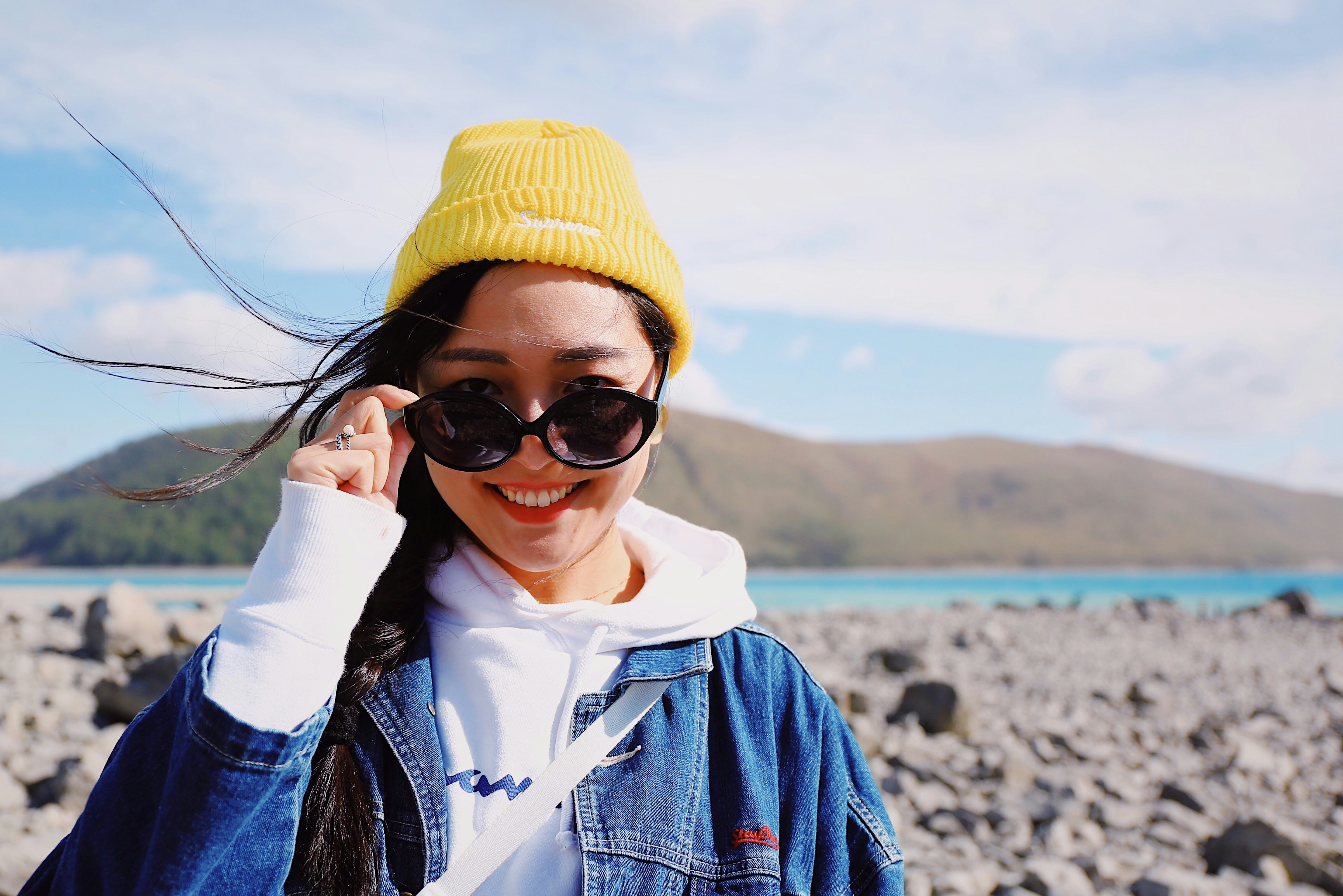 Jennifer S., ATOS Wellness client, smiling outdoors while wearing sunglasses and a yellow beanie. Her testimonial praises the spacious room, friendly staff, and the personalized care from Hanisha, stating she feels relaxed and refreshed after every visit.