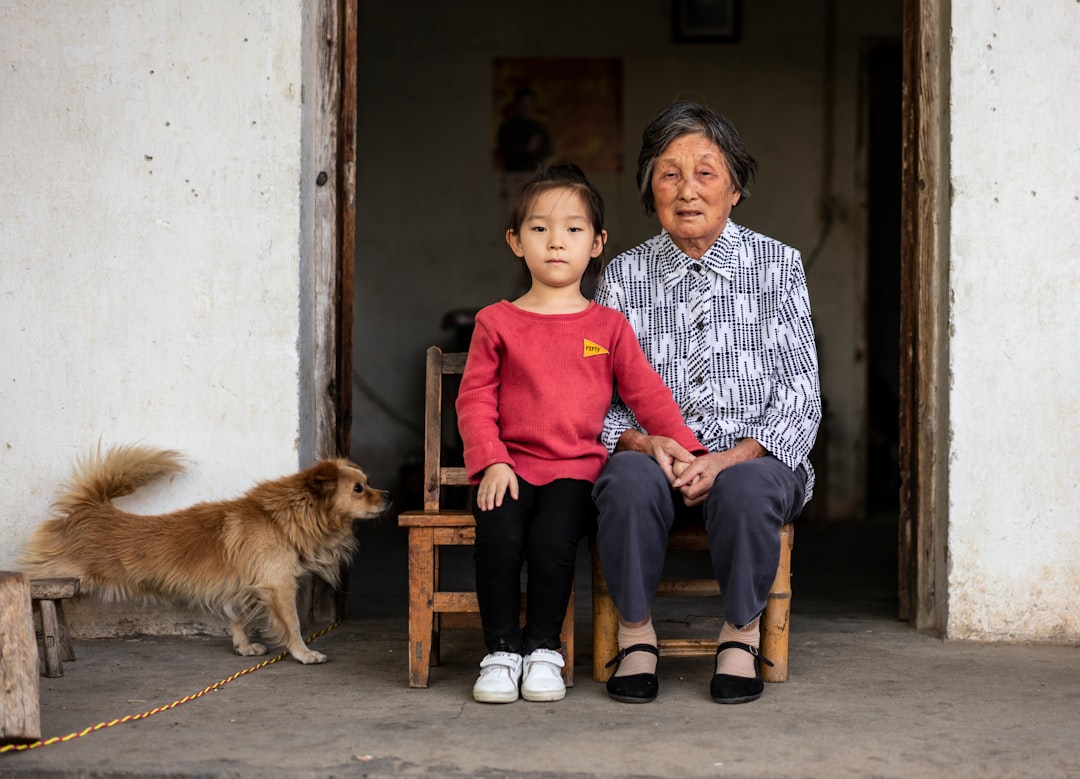 girl and woman sitting near brown dog