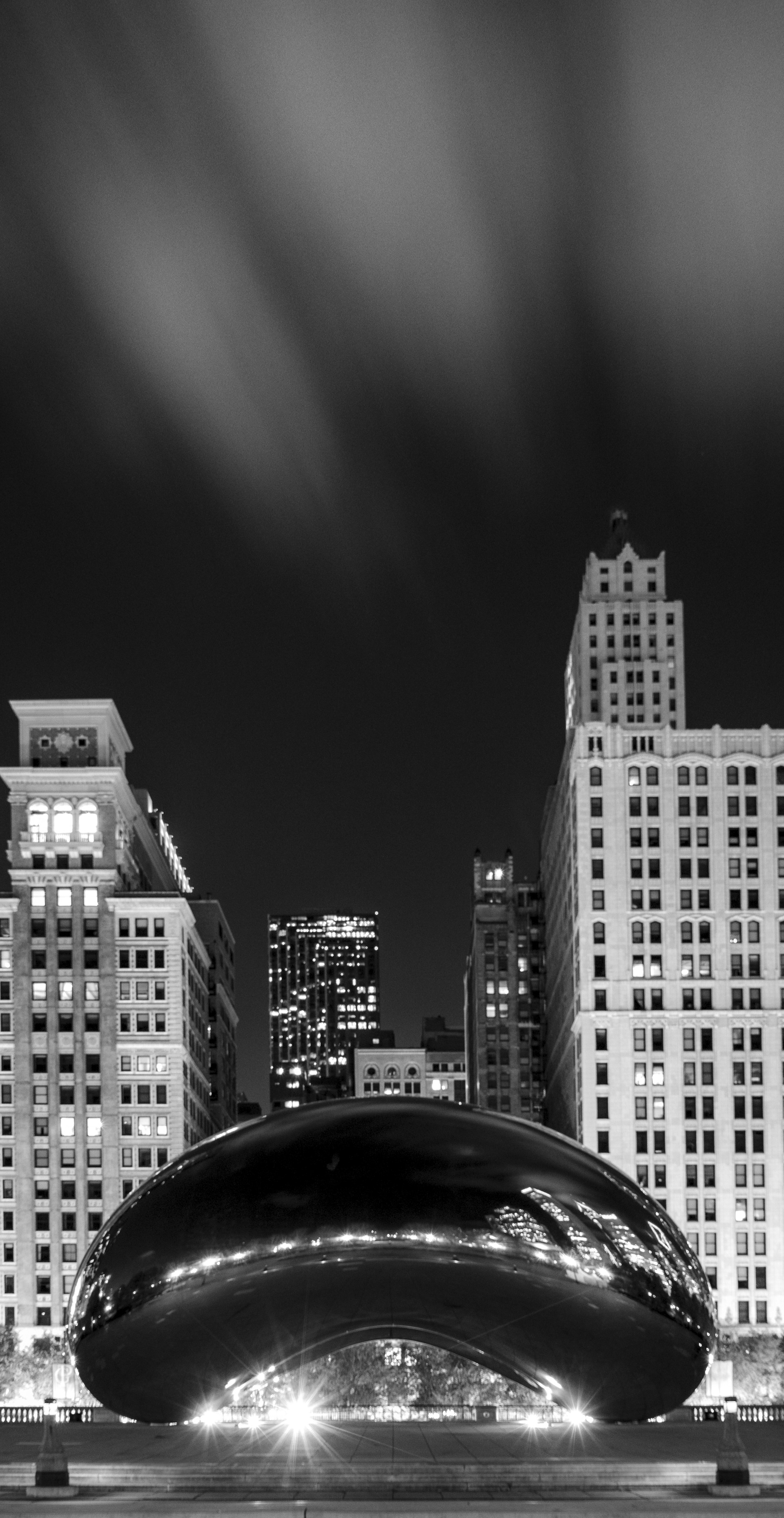 A dramatic black and white cityscape capturing the hustle of a rainy evening downtown.