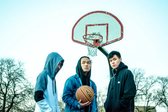 three men wearing hoodie near basketball hoop