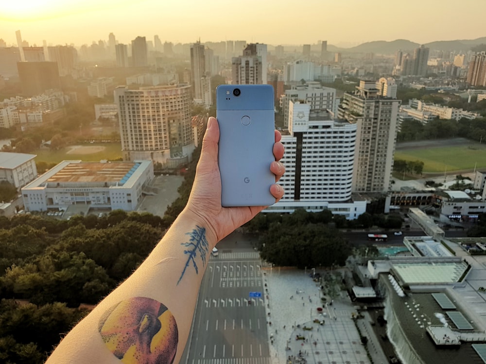 person showing grey smartphone with high rise building view