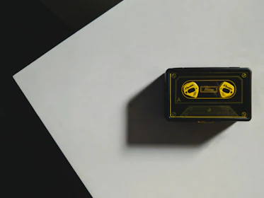 A vintage cassette tape labeled 'Pretty in Clink Podcast' resting on a steel table with barbed wire shadows.