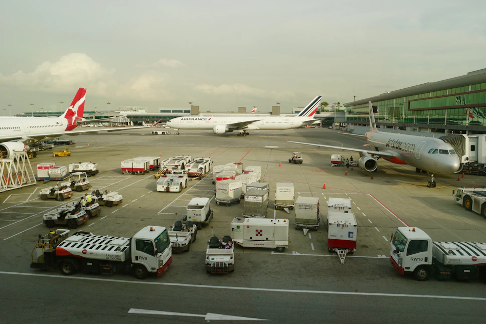 white and red trucks parked beside gray and white plane