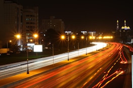 A nighttime cityscape of Dubai with a delivery scooter speeding through illuminated streets.