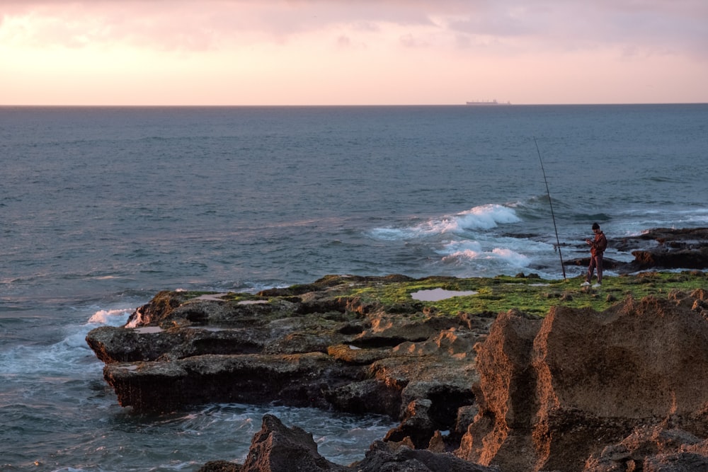 man standing near the edge of a cliff during sunset