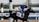 A jockey in a blue uniform rides a racehorse during a race, with the number 10 visible on the horse's harness. The background includes a racecourse with blurred spectators and palm trees.