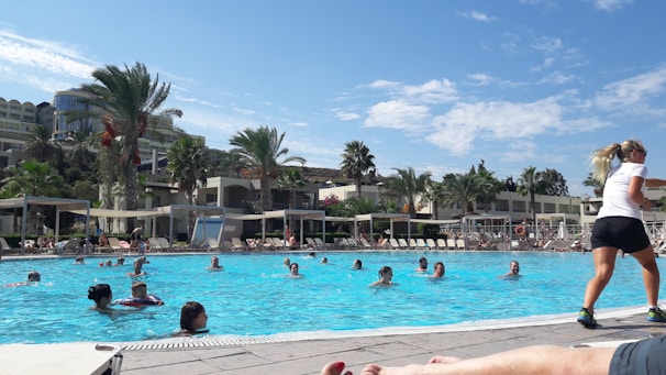 Residents enjoying the swimming pool surrounded by green gardens on a sunny day.