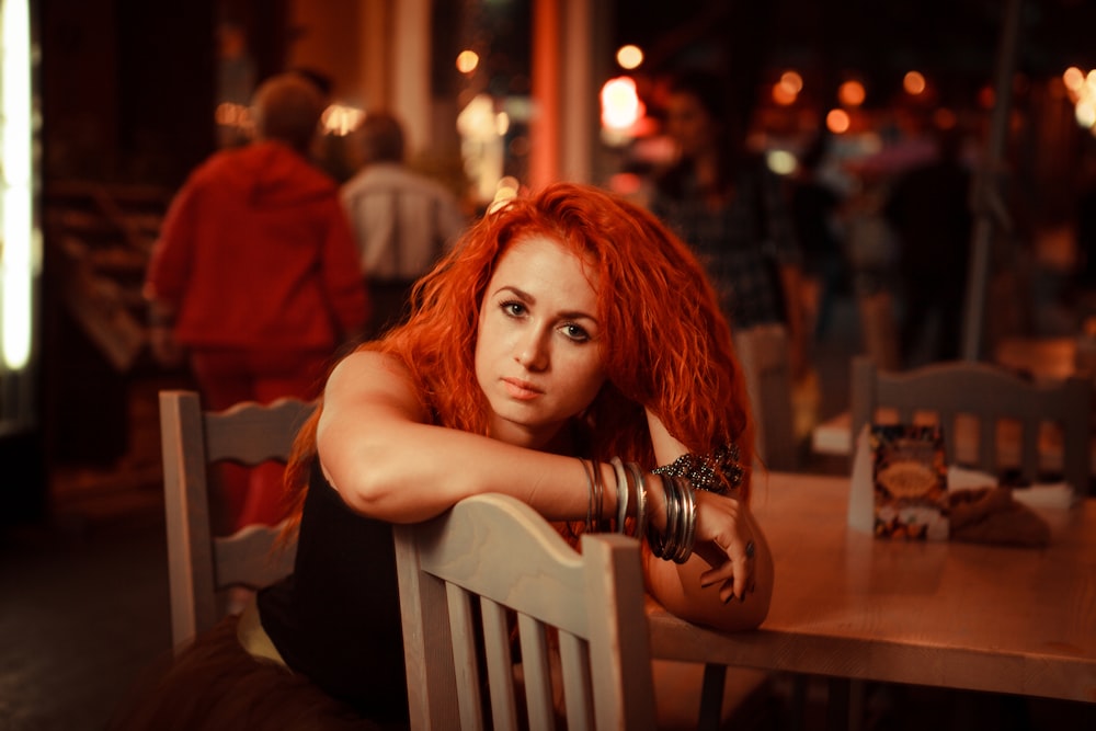 woman wearing black tank top sitting on chair near table