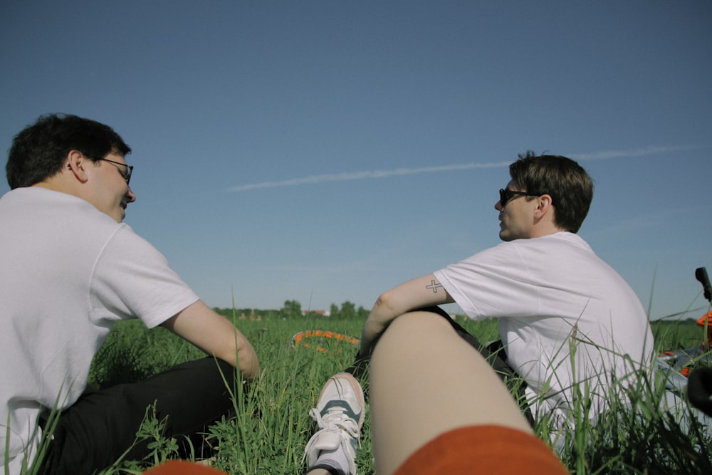 deux hommes portant des chemises blanches assis sur un sol vert