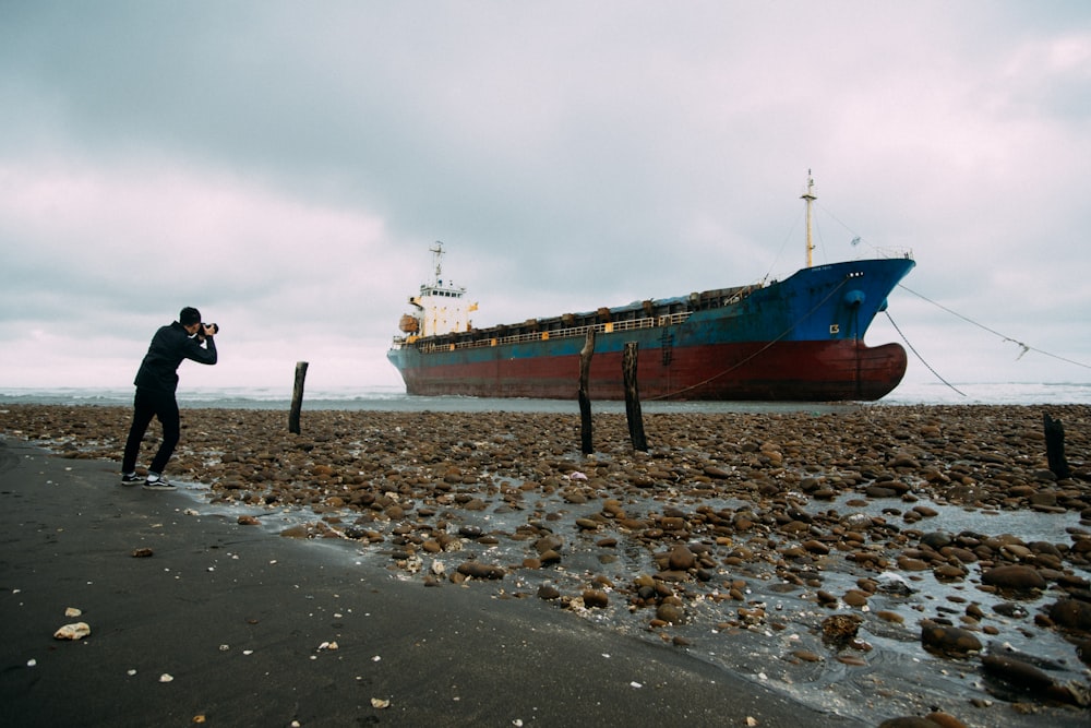 man taking a picture of a cargo ship during day