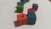 Colored wooden cubes with Arabic letters on them are scattered on a white surface. The cubes are in different colors such as orange, blue, red, green, and purple, arranged at different angles.