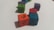Colored wooden cubes with Arabic letters on them are scattered on a white surface. The cubes are in different colors such as orange, blue, red, green, and purple, arranged at different angles.