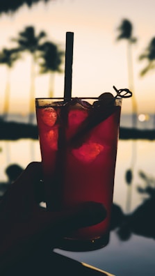 Close-up of sun-kissed hands holding chilled cocktails against a backdrop of turquoise waters.