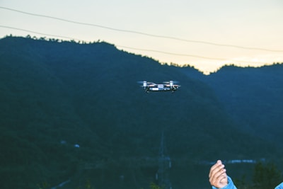 Drone flying over a mountainous terrain capturing lidar data at sunset.