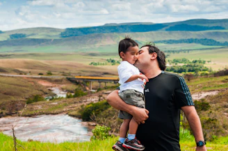 man kissing boy cheek during daytime