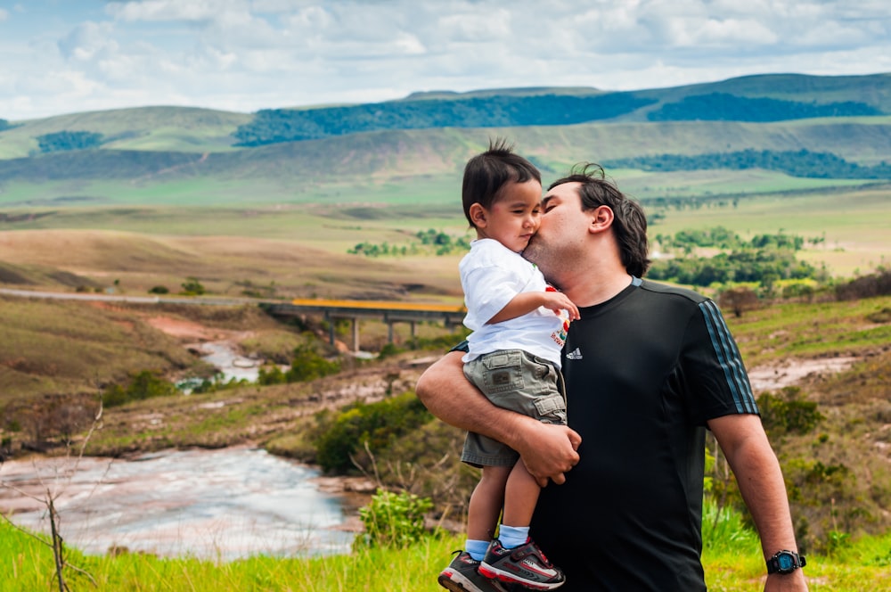 man kissing boy cheek during daytime