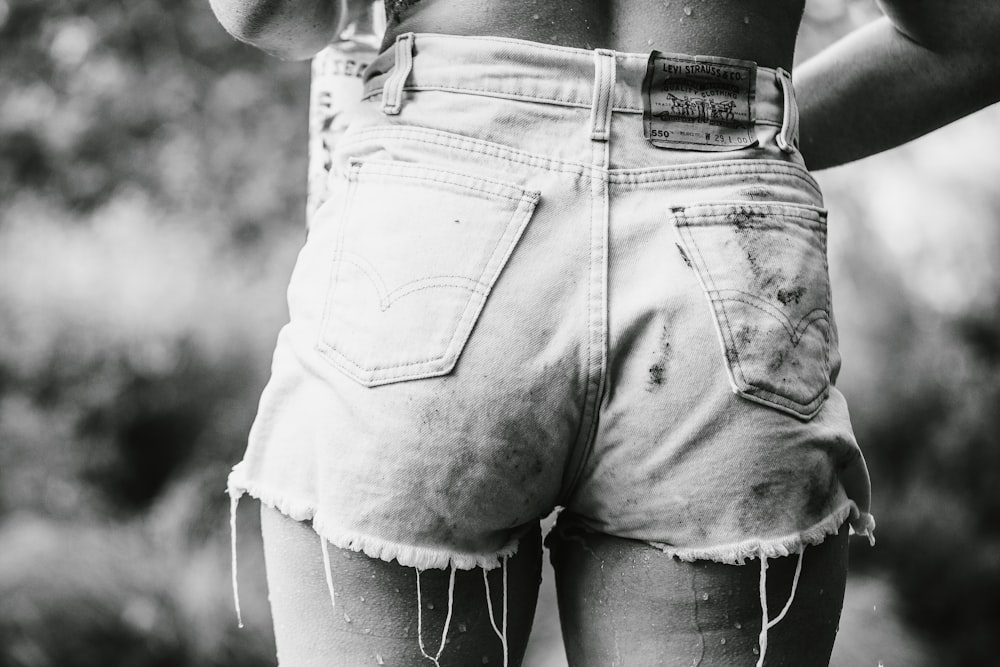 person wearing denim short-shorts in grayscale photography