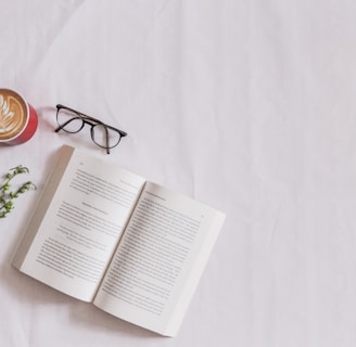 book page beside eyeglasses and coffee