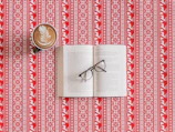 Stylish aviator sunglasses perched on an open book beside a cup of coffee.