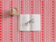 An open ebook on a wooden desk with a cup of coffee and glasses nearby.