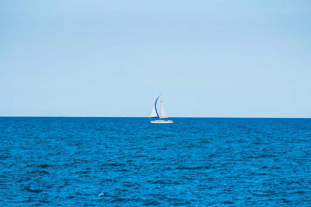 white sailboat in the middle of the ocean during day