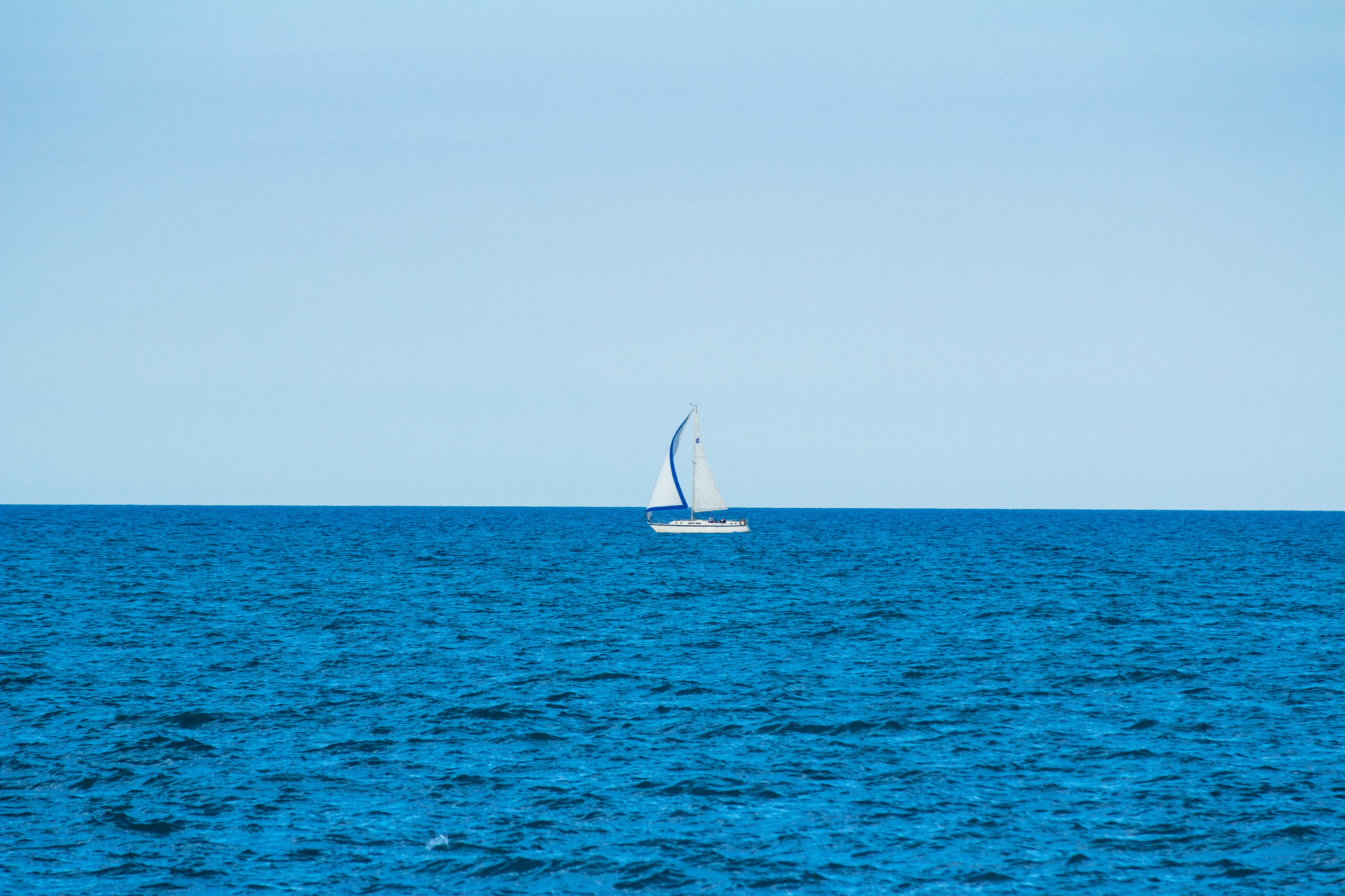 white sailboat in the middle of the ocean during day